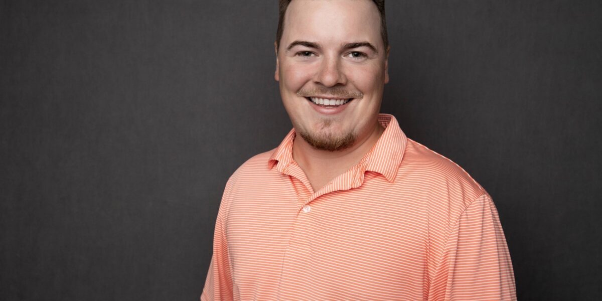professional portrait of Scott Ellis smiling in an orange polo