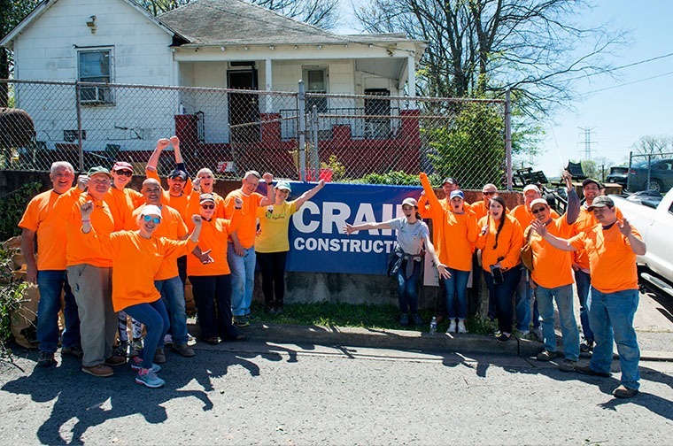 crain workers wearing bright green matching shirts in a group shot in front of a company banner outside