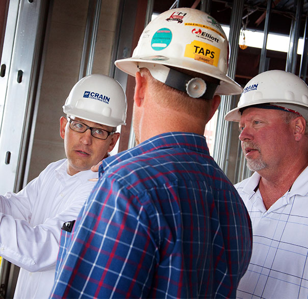 Crain construction workers in discussion wearing hard hats