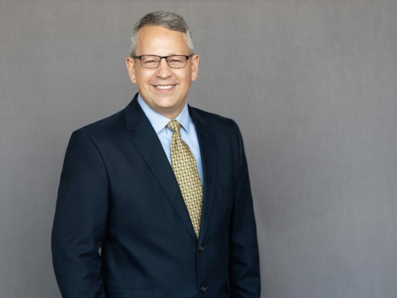 Portrait of James Williams, Senior Project Manager, in a professional setting smiling wearing a suit.