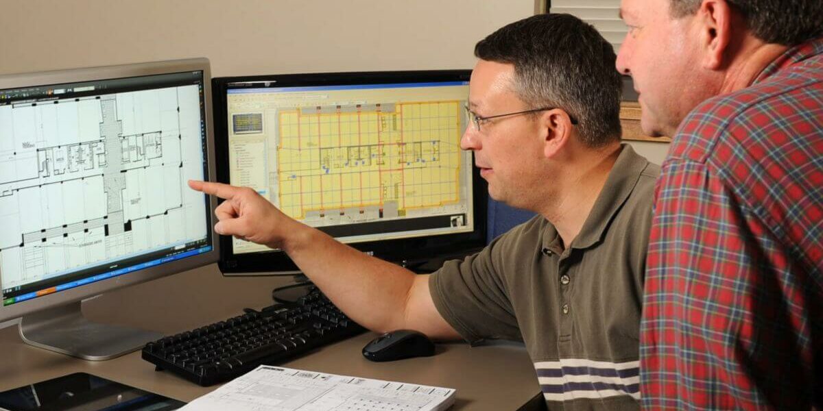 A contractor and an architect discussing a project while pointing at a computer.
