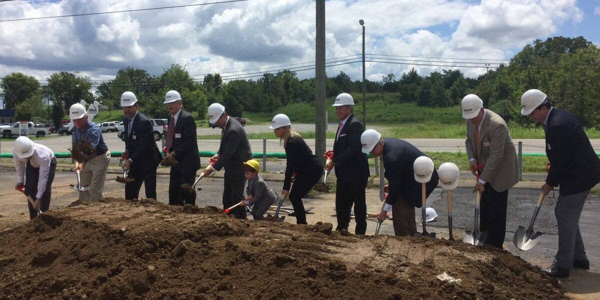 Crain employees breaking ground with shovels and hard hats at an unnamed job site on a sunny day