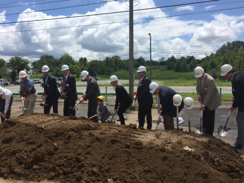 Crain employees breaking ground with shovels and hard hats at an unnamed job site on a sunny day