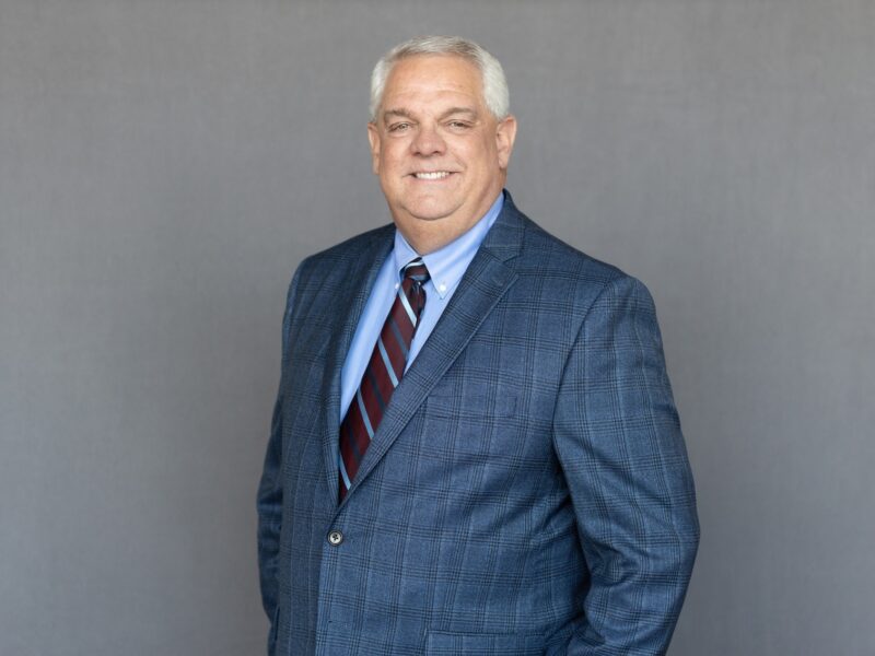 Portrait of Jim Pedigo wearing professional attire, with a friendly smile, in a well-lit indoor setting.