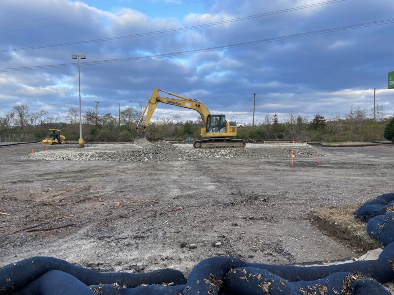 An excavator scooping gravel on a construction site.