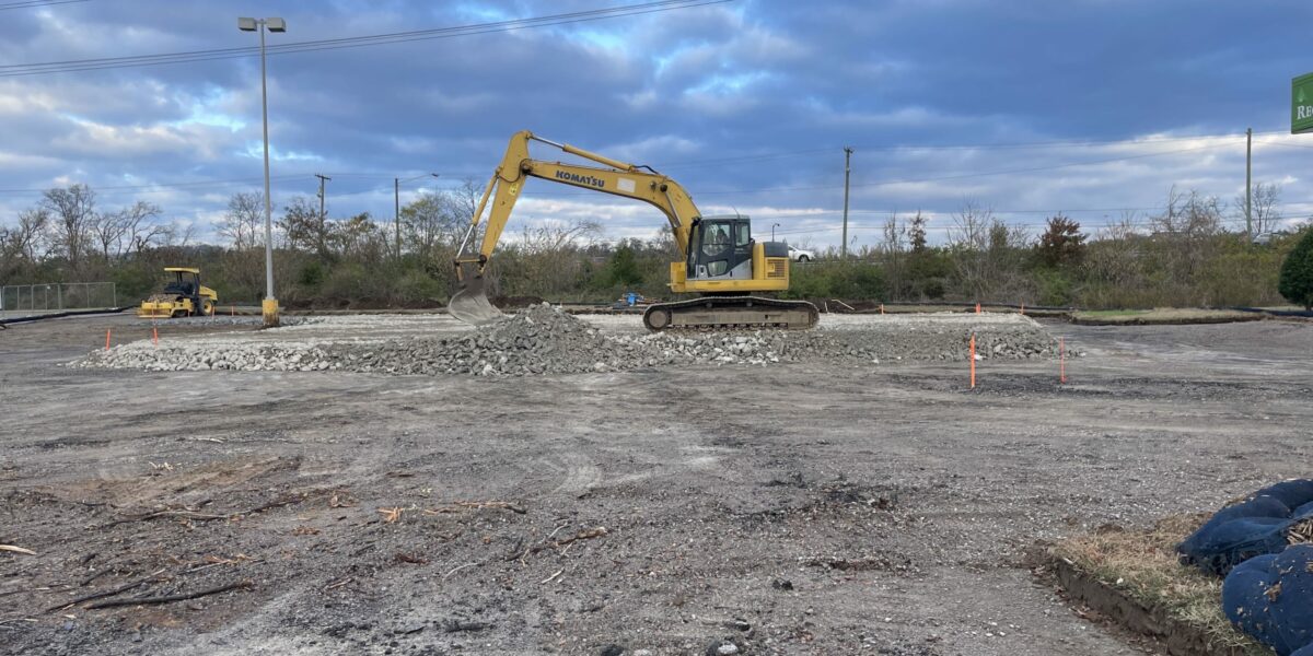 An excavator scooping gravel on a construction site.