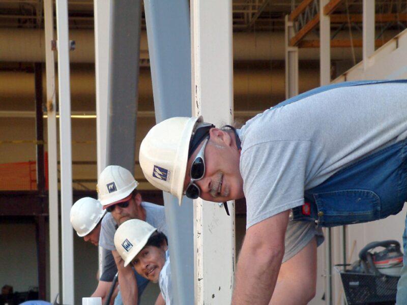Smiling construction workers standing over beams.