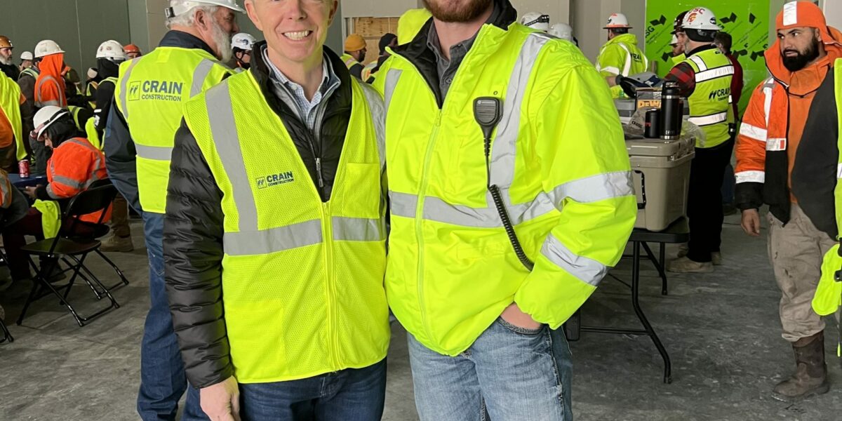 Smiling roofers in construction vests and hard hats.