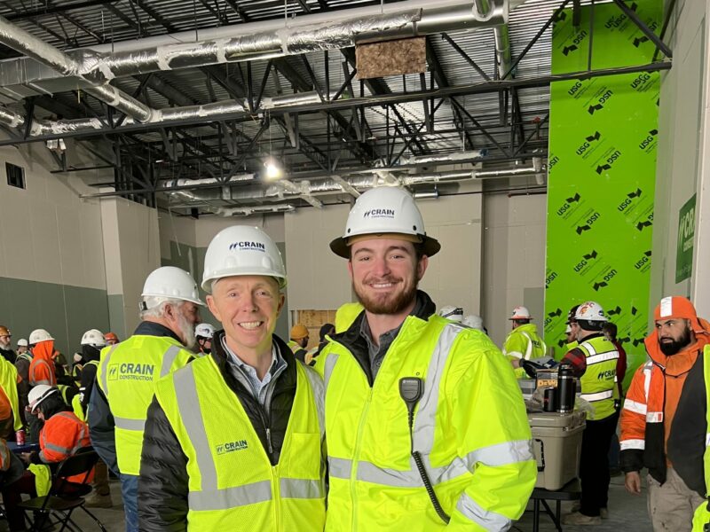Smiling roofers in construction vests and hard hats.
