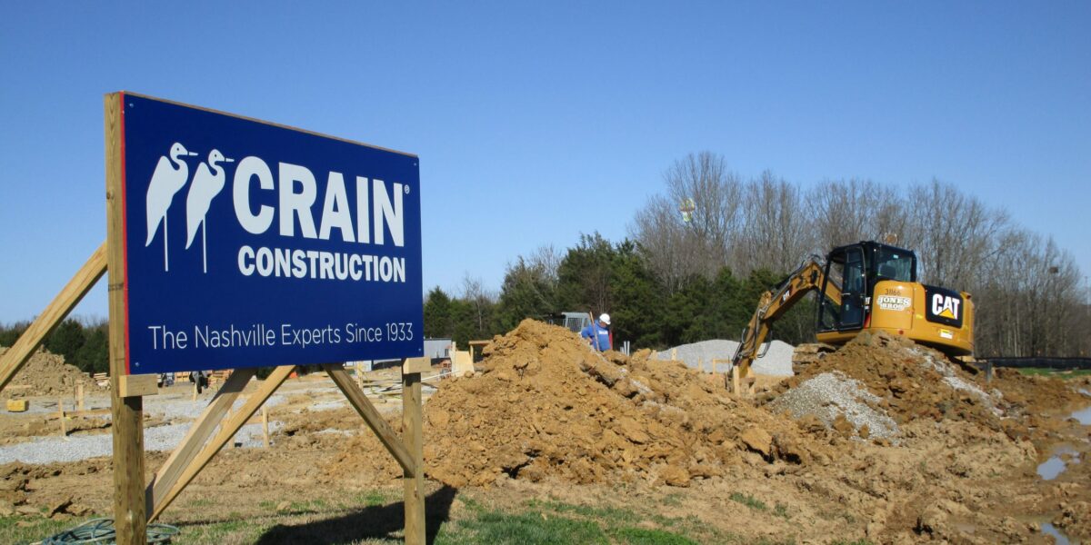 A Crain Construction sign on an active jobsite with dirt work going on behind it.